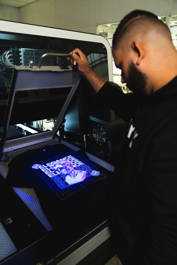 Impressora DTG em operação com arte iluminada em luz UV