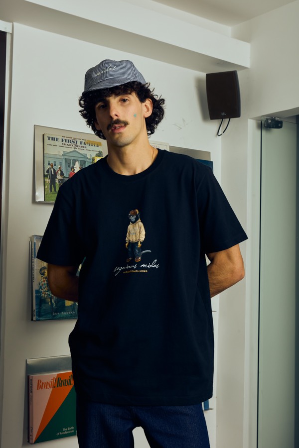 Camiseta azul-marinho com estampa “Midas Touch” nas costas, vista do Rio de Janeiro ao fundo
