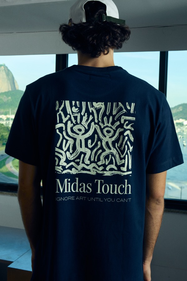 Camiseta branca com estampa de frutas cítricas e o texto “Midas Touch” nas costas