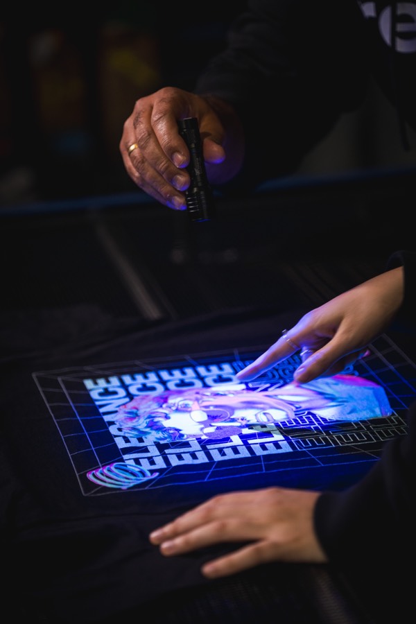 Conferência de qualidade da estampa DTG sob luz UV na produção Remix On Demand